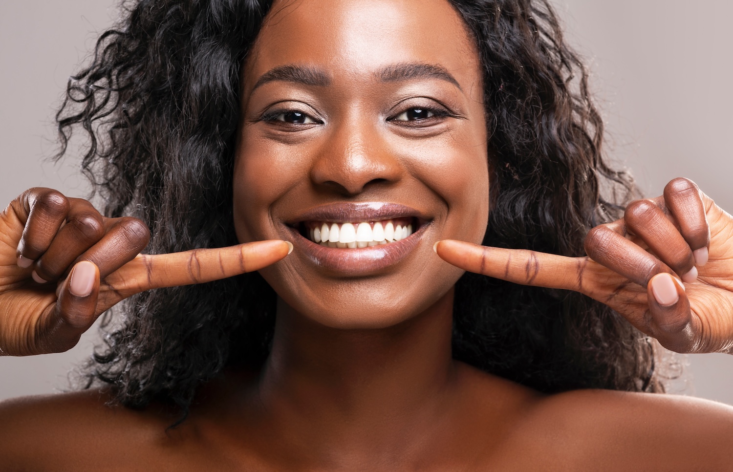 woman pointing to her bright teeth